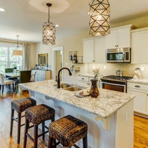  "Traditional kitchen with Giallo Ornamental granite countertops, white cabinets, and geometric pendant lights"